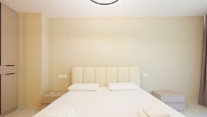 A hotel room with a bed, two pillows, a nightstand, a bedside table, and a box. - Sanpietro Vacation Villa 014 (Ishëm)