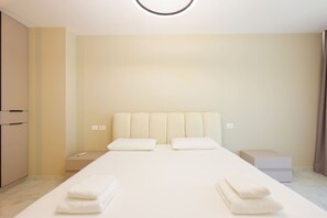 A hotel room with a bed, two pillows, a nightstand, a bedside table, and a box. - Sanpietro Vacation Villa 014 (Ishëm)
