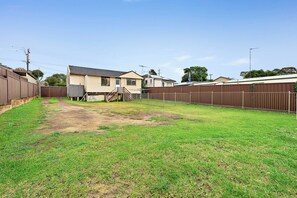 A residential backyard with a house, a wooden fence, and a dirt path. - Cozy 5BR Family Home at St Marys (Saint Marys)