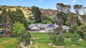 A residential property with a pond, a house with a large garage, and a hilly landscape in the background. - “Southern Highlands Estate”, Private Rural Oasis. (Sutton Forest)