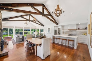 A spacious kitchen with a large island, wooden beams, and a chandelier.