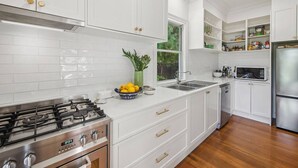 A modern kitchen with white cabinetry, stainless steel appliances, and a window providing natural light. - “Southern Highlands Estate”, Private Rural Oasis. (Sutton Forest)