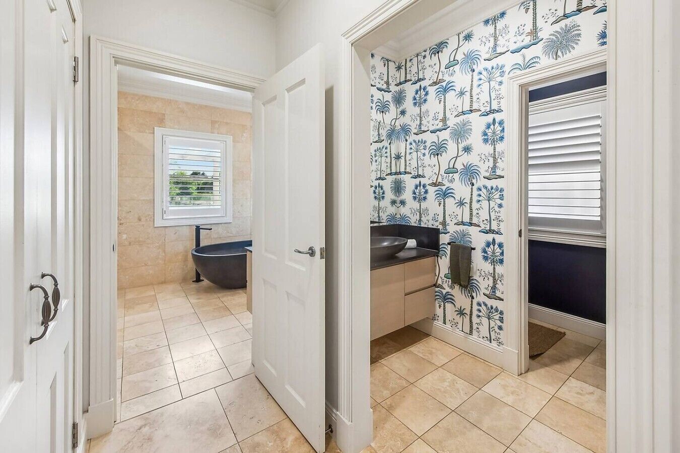 Un baño con bañera, lavamanos y ventana con persianas.