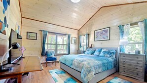 Ein Schlafzimmer mit Bett, Stuhl, Kommode, Schreibtisch und Fenster.
