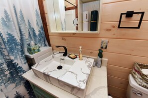 Une salle de bain avec un lavabo en marbre, des murs recouverts de panneaux en bois, un miroir et un porte-serviettes.