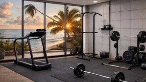 A gym with a treadmill, barbell rack, and weights. - Vigie Beach Suite 1 (Castries)