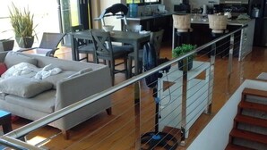 A modern living room with a sofa, dining table, chairs, and a kitchen area in the background. - Vigie Beach Suite 1 (Castries)
