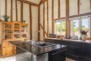 A kitchen with a central island, wooden cabinets, and a view of the outdoors. - Moles Meadow (4), Middleton (Middleton)