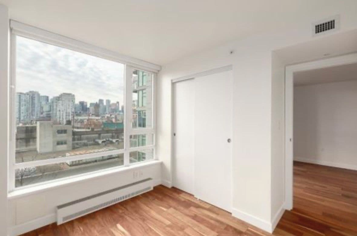 A room with a large window, white walls, and a radiator.