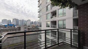 A high-rise building with multiple balconies, large windows, and a view of a cityscape.