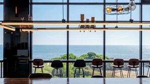 Un restaurante con vistas al mar, ventanas amplias y sillas modernas.
