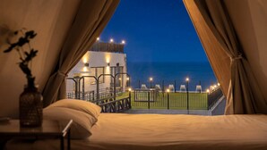 Una habitación con una cama, vista al mar y una terraza con sillas.