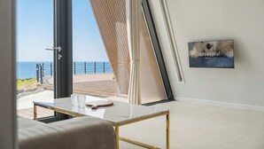 Una habitación moderna con una mesa de vidrio, un sofá y vista al océano.