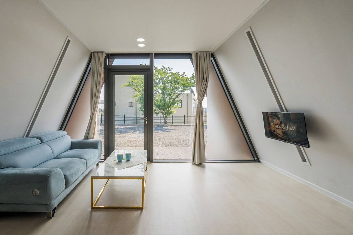 Una sala de estar moderna con un sofá, una mesa de centro y un televisor montado en la pared.