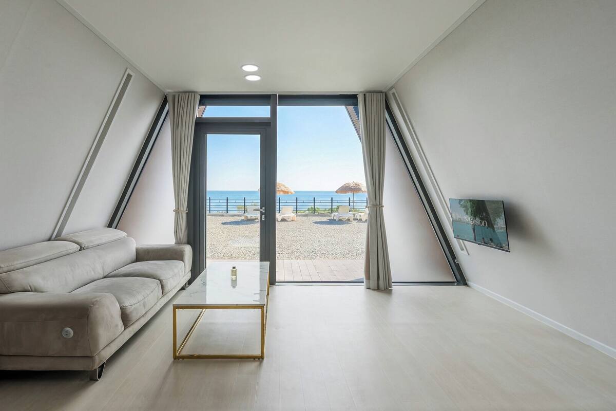 Una habitación moderna con sofá, una mesita de centro y vistas a la playa.