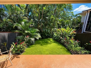 A well-maintained garden with a lawn, various plants, and a wooden bench. - Walk to Sandy Beach, Restaurants and Shops (Lahaina)