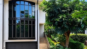 A modern house with a large window, a garage, and a staircase leading to the entrance. - Walk to Sandy Beach, Restaurants and Shops (Lahaina)