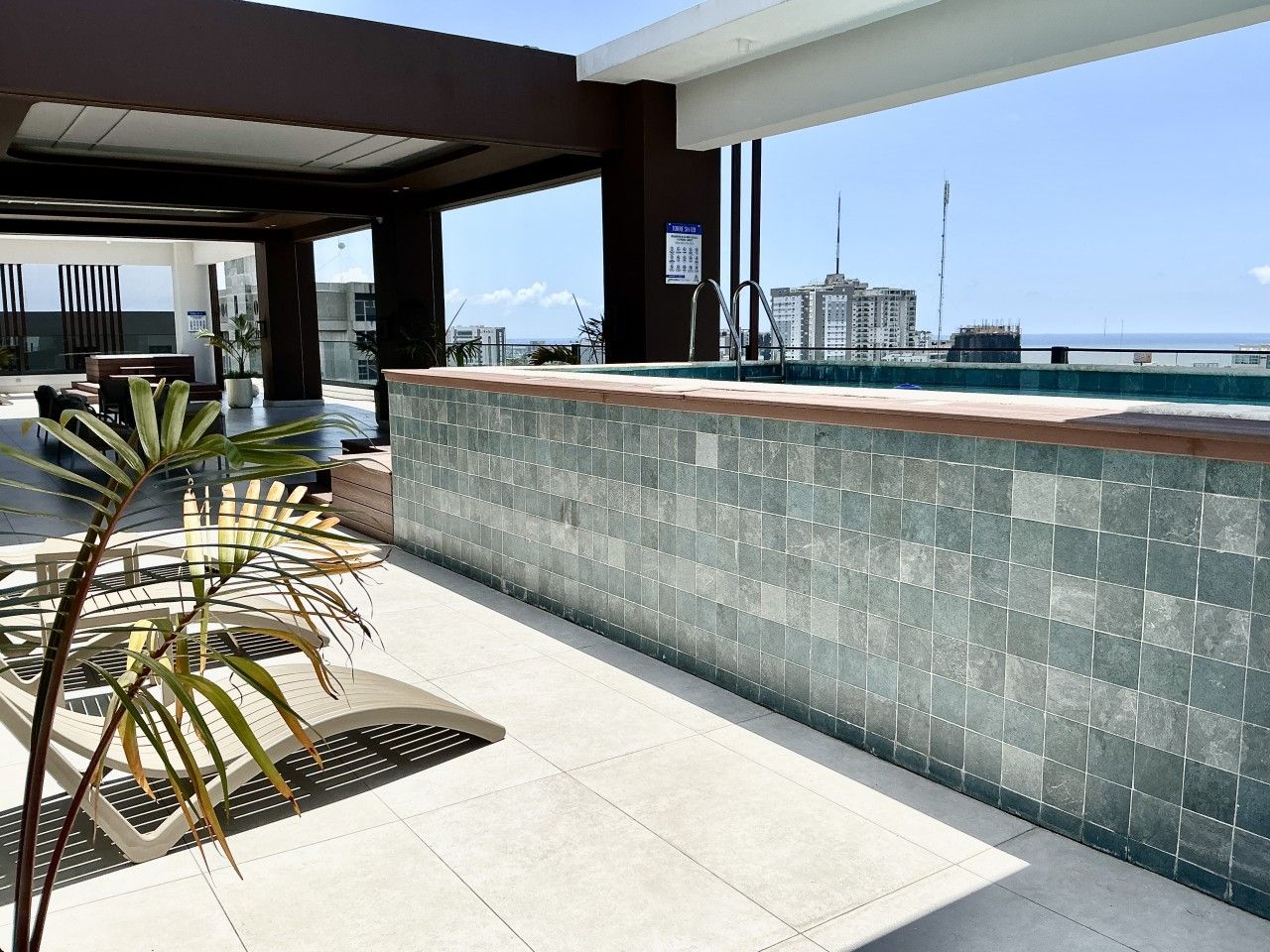 Eine Dachterrasse mit Pool, Sitzgelegenheit und Blick auf die Stadtlandschaft.
