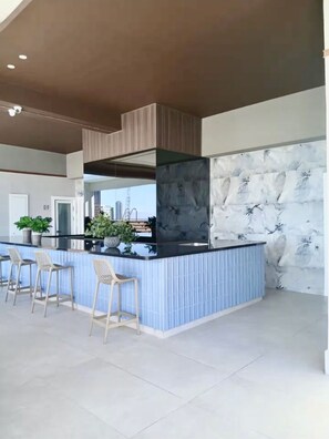 Una cocina moderna con una isla central, taburetes de bar y un ventanal grande.