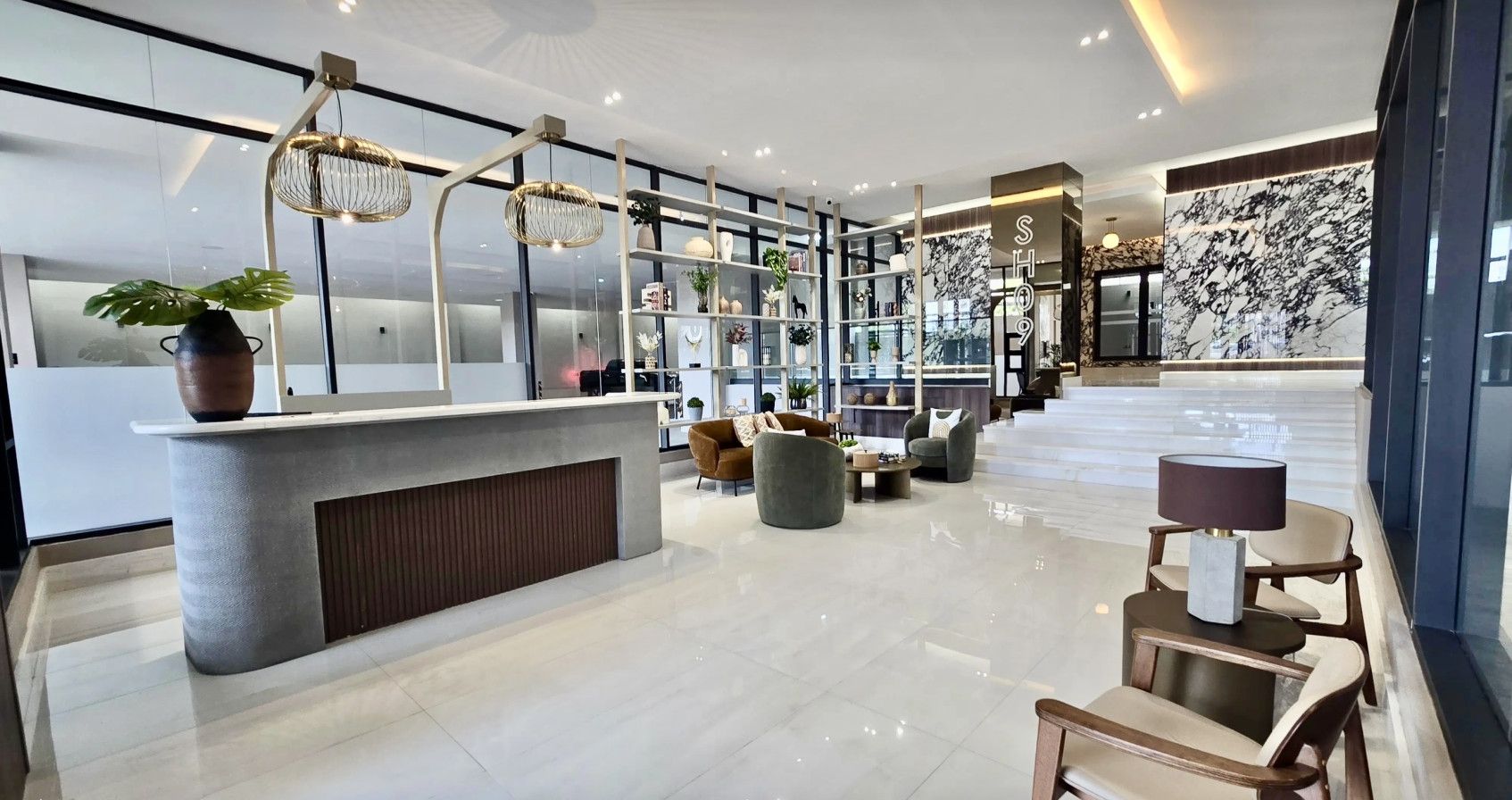 A modern hotel lobby with a reception desk, seating area, and a marble wall.