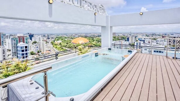 A rooftop infinity pool with a city view, a wooden deck, and a sign with partially visible text. - Modern Luxury Retreat Residence XX11 La Esperilla (Santo Domingo)