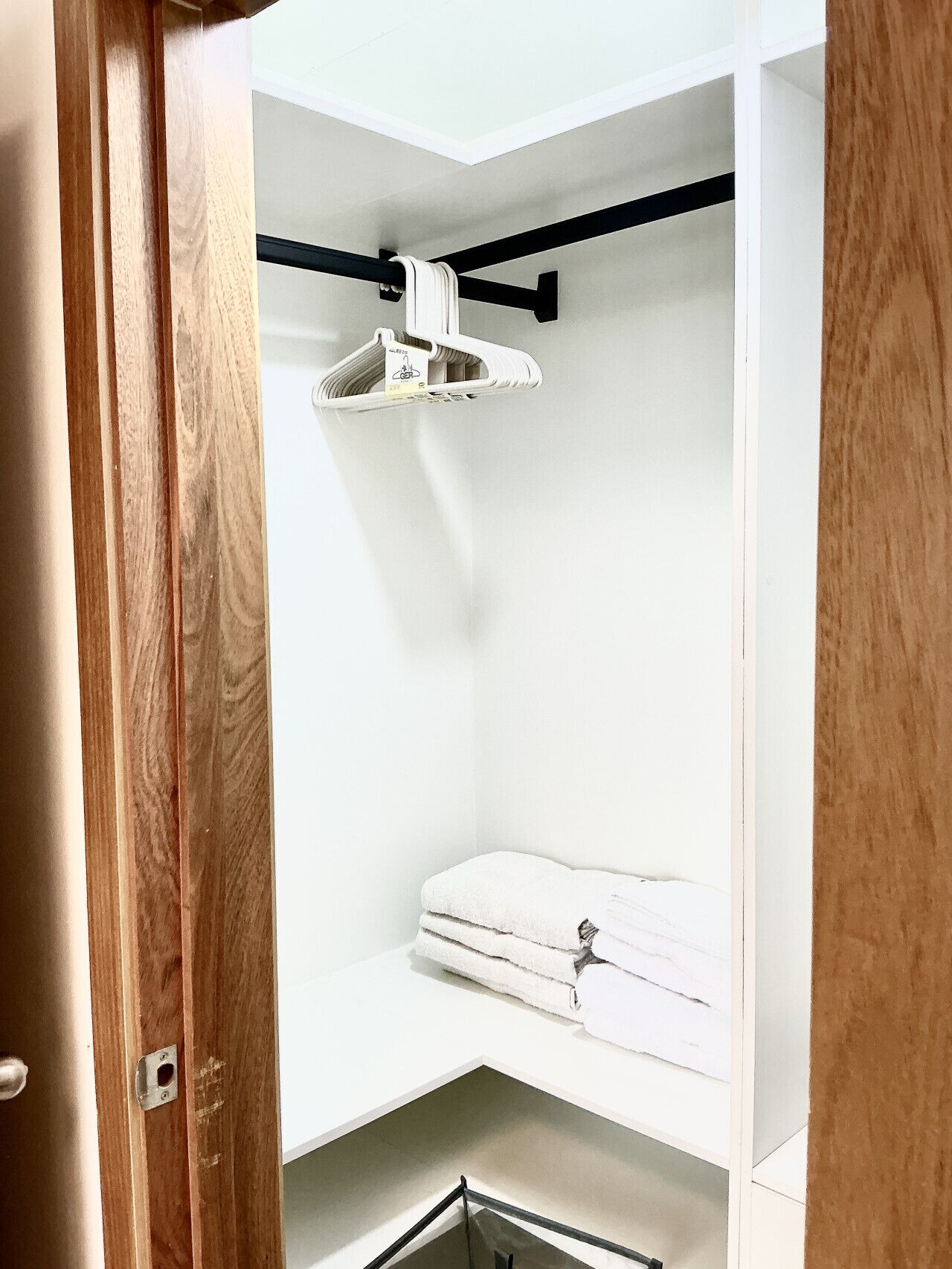 Un placard avec une tringle à vêtements, une serviette pliée et une étagère en métal.