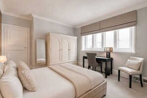 Ein Schlafzimmer mit einem Bett, einem Schreibtisch, einem Stuhl und einem Kleiderschrank.