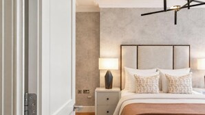 Una camera da letto con un letto, abat-jour, comodino e una lampada a soffitto moderna.