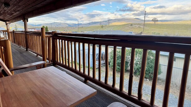 A wooden deck with tables and a view of a hilly landscape. - Merritt Lodge Motel (Merritt)