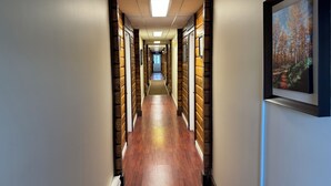 A hallway with wooden paneling, a framed picture on the wall, and a door at the end. - Merritt Lodge Motel (Merritt)