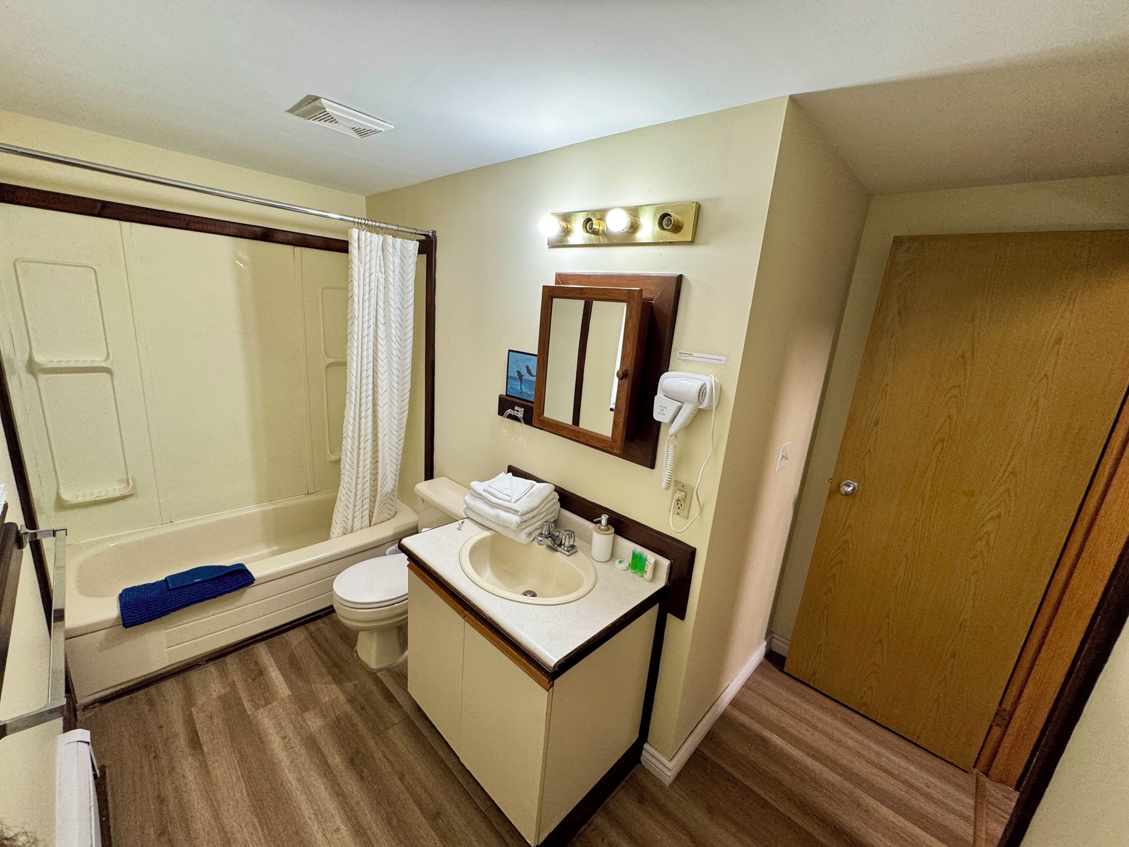 A standard hotel bathroom with a shower, toilet, sink, and a mirror above the sink.