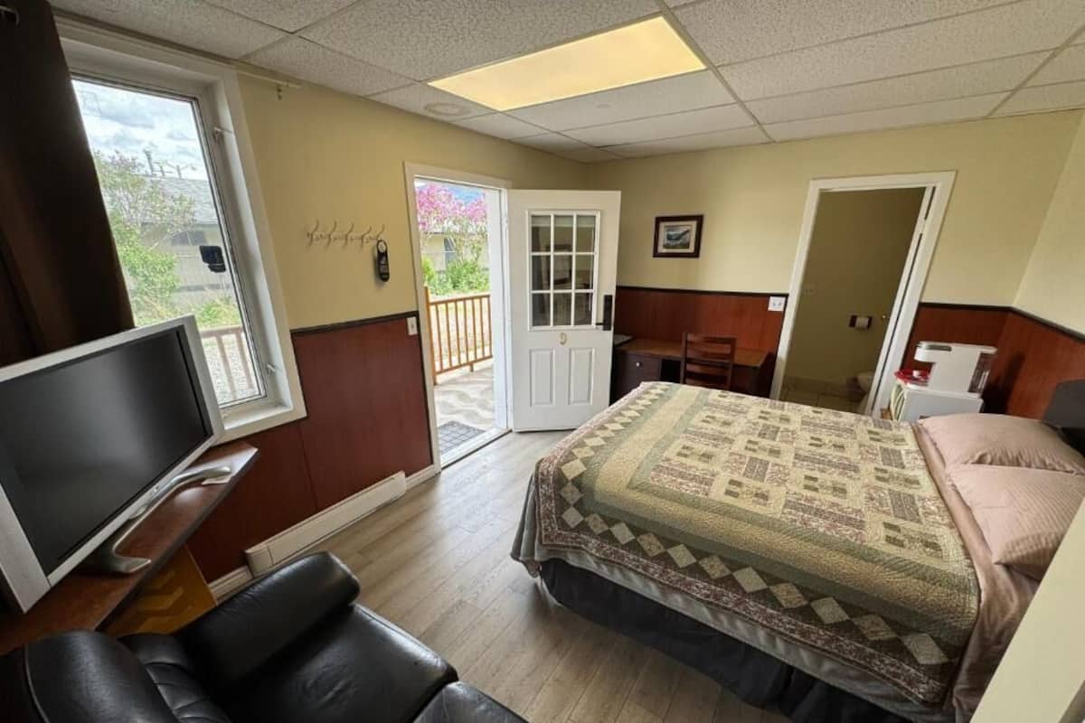 Una habitación con una cama, televisión, escritorio y una silla.