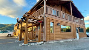 A wooden building with a balcony, a sign indicating it's open, and a car parked in front. - Merritt Lodge Motel (Merritt)