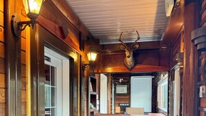 A cozy interior with wooden walls, a leather sofa, a deer head mounted on the wall, and a bar area. - Merritt Lodge Motel (Merritt)