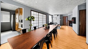 Uma cozinha moderna com armários de madeira, uma janela grande e um espaço de refeições com uma mesa de madeira comprida e cadeiras pretas.
