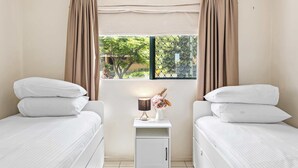 A hotel room with two beds, a nightstand, a lamp, and a window with curtains. - Quiet Family Stay in Albion | Parking & City Views (Albion)