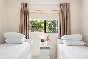 A hotel room with two beds, a nightstand, a lamp, and a window with curtains. - Quiet Family Stay in Albion | Parking & City Views (Albion)