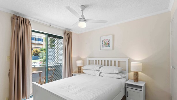 A bedroom with a bed, nightstands, a ceiling fan, a window with curtains, and a small balcony. - Quiet Family Stay in Albion | Parking & City Views (Albion)