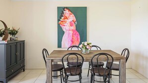A dining area with a wooden table, black chairs, a vase with flowers, and a painting of a bird on the wall. - Quiet Family Stay in Albion | Parking & City Views (Albion)