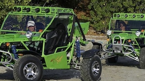 Two green off-road vehicles with seats and a steering wheel, parked on a dirt surface. - Vigie Beach Premium (Castries)