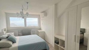 A bedroom with a bed, a chandelier, a window, a wardrobe, and a radiator. - Villa with air conditioning, pool and terrace with sea view (Imperia)