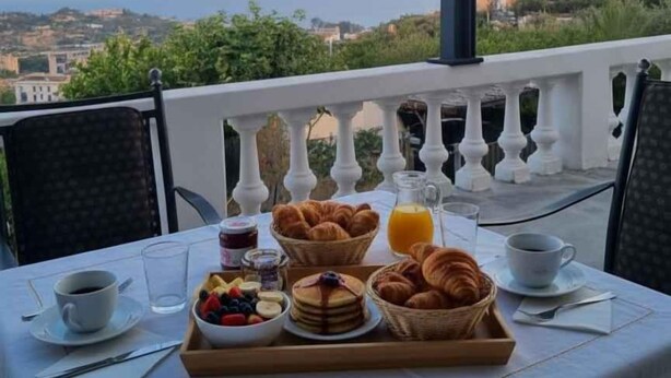A table with breakfast items and a view of the sea and town. - Villa with air conditioning, pool and terrace with sea view (Imperia)