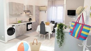 Un espacio habitable compacto con kitchenette, comedor y una pequeña zona de estar.