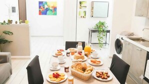 Un comedor con una mesa dispuesta para el desayuno, una lavadora y una planta al fondo.