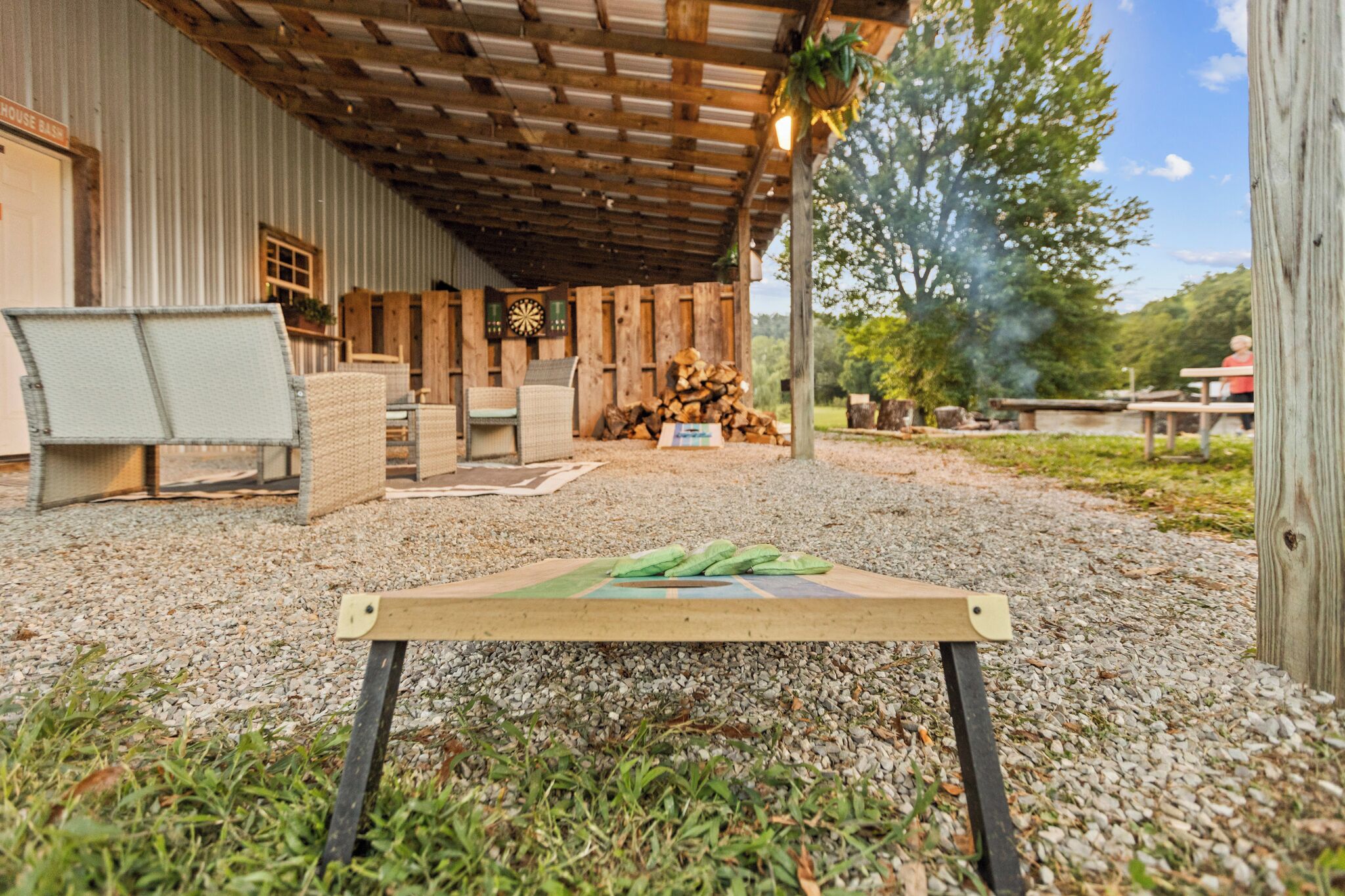 Un'area salotto esterna rustica con tavolo e sedie in legno, un portico coperto e vista su un fiume.