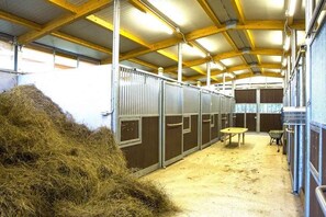 A stable with metal stalls, hay, and a table. - Holiday flat with balcony (Borghetto d'Arroscia)