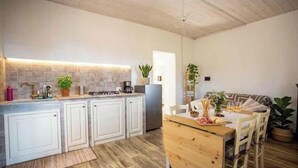 Een keuken met witte kastjes, een houten eettafel en een hanglamp.