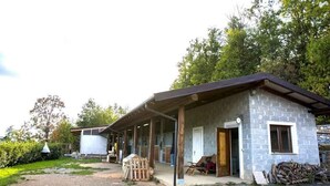 Een gebouw van steen met een overdekte veranda, een deur en een raam.