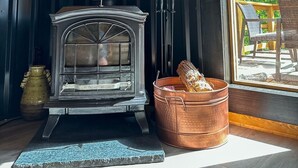 En vedeldad kamin i en stuga med utsikt över utomhusmöblerna.