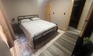 A bedroom with a bed, a wooden door, a rug, and a potted plant. - Cast a line. Cruise the lake. Explore miles of nearby trails—or simply relax. (Warsaw)
